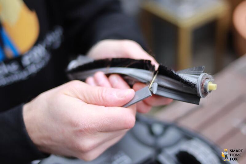 Haare werden mit Hilfe eines Reinigungswerkzeugs aus der Bürste des Ecovacs Deebot X1 OMNI entfernt